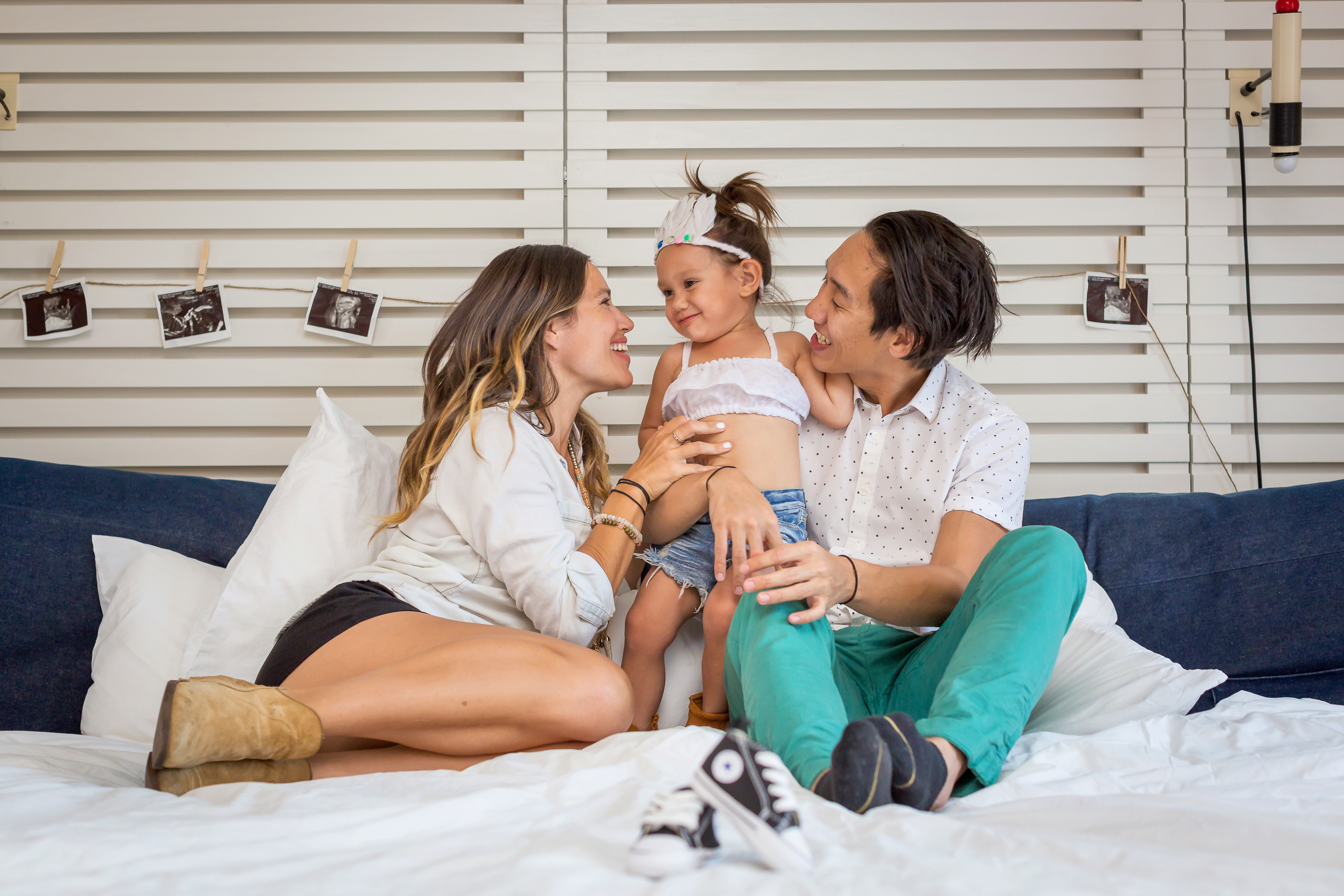 Family of three smiling on the bed at the Ace Hotel